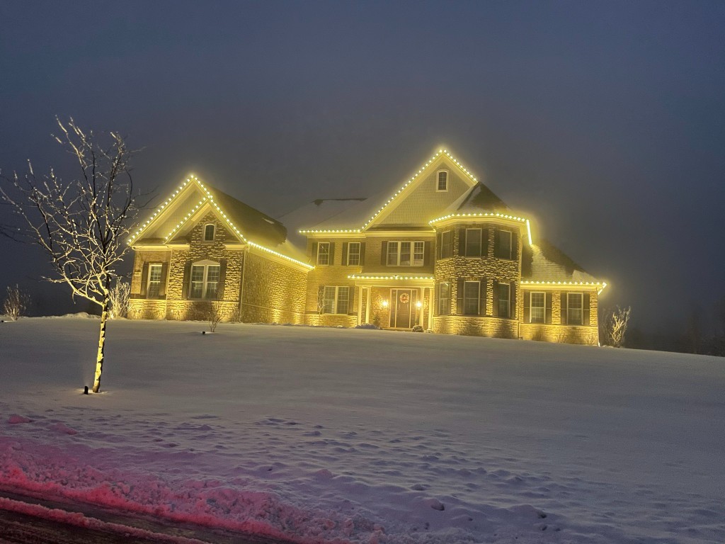 Luxury Fox Valley home with warm white holiday lights in the snow
